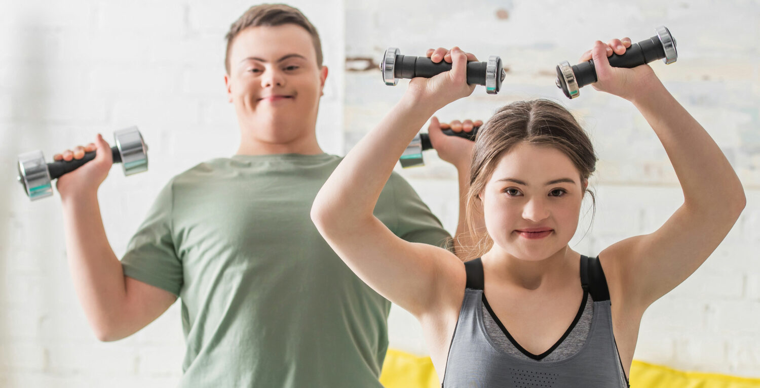 young white woman and young white man, both with Down syndrome, lift dumbells