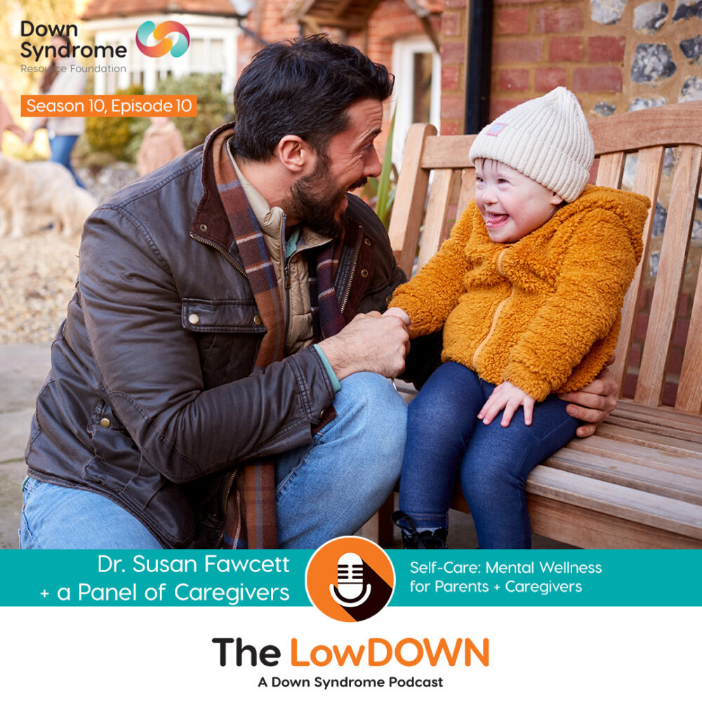 dark haired man with beard wearing brown jacket and blue jeans kneels beside his young daughter with Down syndrome who is sitting on a bench, wearing a white toque, orange coat and blue jeans